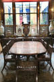 Dining table & trellis-back chairs by John Robins with sideboard with ceramics & courtyard window beyond at Sir John Soane's Museum. London, United Kingdom.