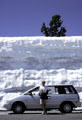 Snowbanks of July tower over cars in highest pass of Lassen Volcanic National Park. CA