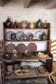 Shelf with early American glass, ceramics, pewter & wooden serving vessels at Old Stone House. Washington, DC.