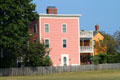 Pink & yellow heritage houses on field leading to Salem's Central Wharf. Salem, MA.