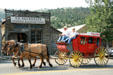 Tourist stagecoach passes before Sauerbier Blacksmith Shop. Virginia City, MT.