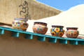Paseo del Pueblo Norte roofline decorated with painted pots. Taos, NM.