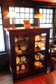 Bookcase with Roycroft ceramics & lamps in dining room at Elbert Hubbard Roycroft Museum. East Aurora, NY.