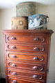 Chest of drawers supporting hatboxes in Layton Home at Old Bethpage Village. Old Bethpage, NY.