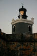 Lighthouse on Morro Fortress shines at dusk. San Juan, PR.