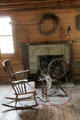 Fireplace, rocking chair & spinning wheel in Gates house at Pioneer Village. Gonzales, TX.