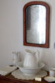 Wash basin & pitcher under mirror in Baetge House at Conservation Plaza. New Braunfels, TX.