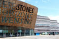 Glass walled entrance & multi-colored Welsh slate building walls at Wales Millennium Centre at Cardiff Bay. Cardiff, Wales.