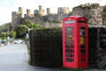 View from harbor area of castle walls & turrets with vintage red phone booth in the foreground. Conwy, Wales.