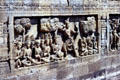 Carved stone relief of archer surrounded by praying men at Borobudur. Indonesia.