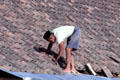 Man repairing tiles on roof. Jogyakarta, Indonesia.