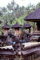 Temple carvings & shrines with thatched roofs. Bali, Indonesia.