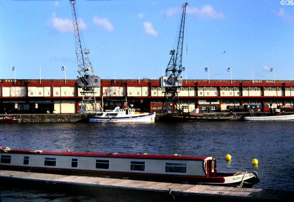 Antique cranes in front of former warehouses at Bristol's Floating Harbour, a tidal by-pass of the Avon River which kept ships from being stranded during low tide after docking at Bristol. Bristol, England.